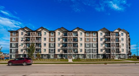 A five story apartment complex with road parking in front