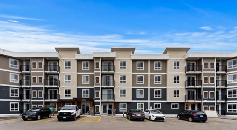 A large apartment building with a parking lot in front.
