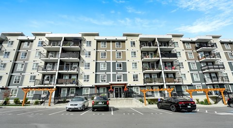 A large apartment complex with cars parked in front.