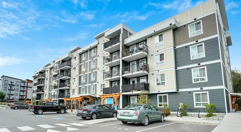 A modern apartment building with cars parked in front.