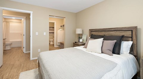 A bedroom with a queen sized bed and a walk in closet leading to a bathroom