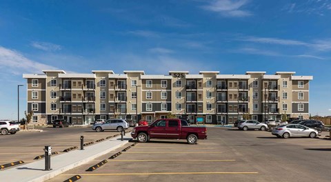A large apartment building with a large parking lot in front