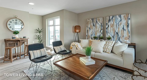 A living room with a white sofa, a wooden table, and a clock on the wall.
