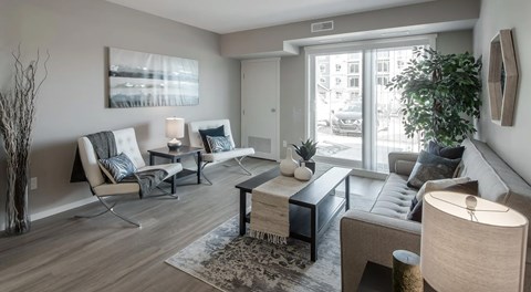 A living room with a couch, chairs, and a coffee table with a large glass sliding door