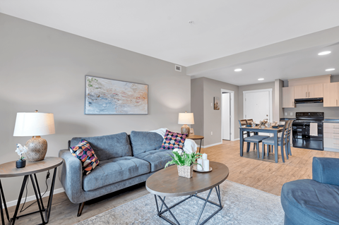A living room with a grey couch, a coffee table, and a painting on the wall.