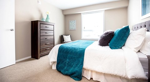A bedroom with a large bed, dresser and large window