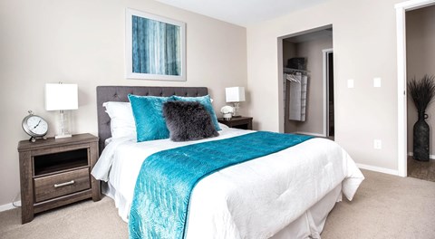 A bedroom with queen sized bed, nightstands, and entrance to walk in closet