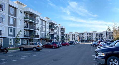 A parking lot with cars and apartment buildings in the background.
