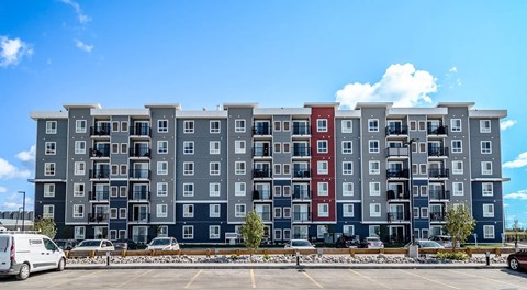 A large apartment building with a parking lot in front.