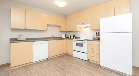 A kitchen with light wooden cabinets and white appliances