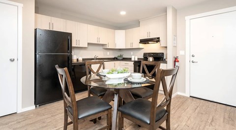Black appliances sit in a kitchen with a table and chairs.