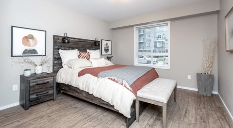 A bedroom with a bed, nightstand, and a window.
