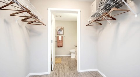 A walk in closet with shelves on either side for hanging clothes, leading to an ensuite