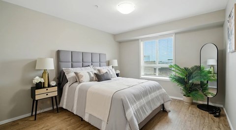 A bedroom with a bed, nightstand, window