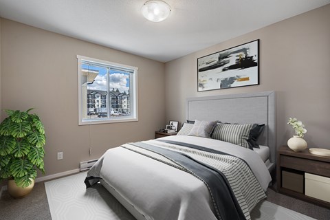 A bedroom with a large bed and a potted plant.