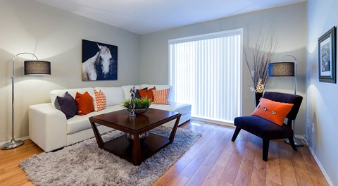 A living room with a small sectional, coffee table and chair with a large glass sliding door