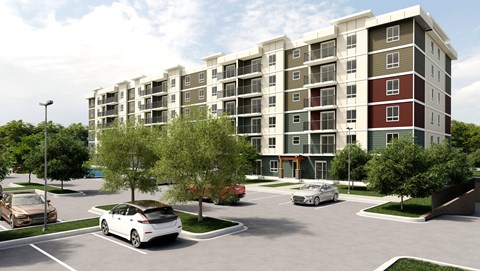 A white car is parked in a parking lot in front of a multi-story apartment building.