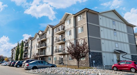 A large apartment building with parking lot in front