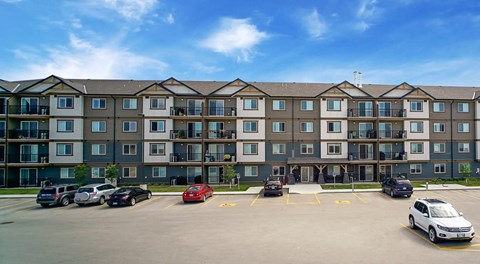A large apartment building with lots of parking in front