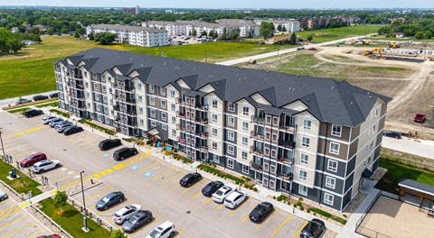 A large apartment complex with a parking lot in front.
