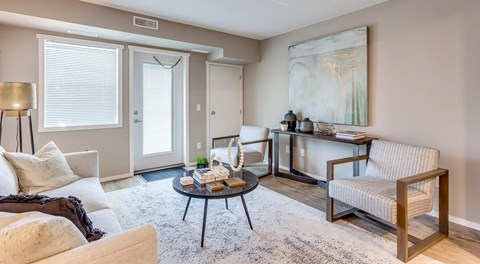A living room with a window balcony door with couches and chairs