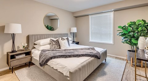A well-lit bedroom with a large bed, night stands and large window