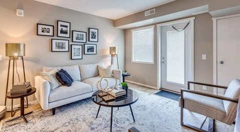 A living room with a white couch, a coffee table, and a chair.