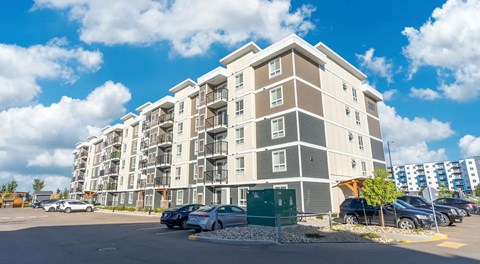 A large apartment building with a parking lot in front.