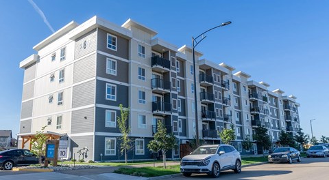 A modern apartment building with cars parked in front.