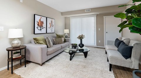 An open living room with couch, coffee table, end tables and chairs. Large glass sliding door on exterior wall