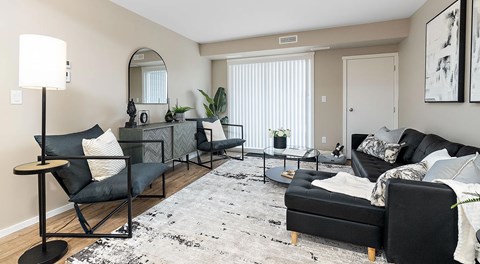 A living room with a small sectional, coffee table and two chairs, a large glass sliding door sits next to the space