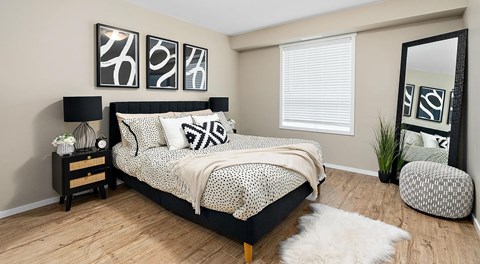 A bedroom with a queen sized bed, two night stands and a large window