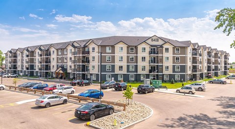 Large Apartment complex with lots of balconies windows and a large parking lot