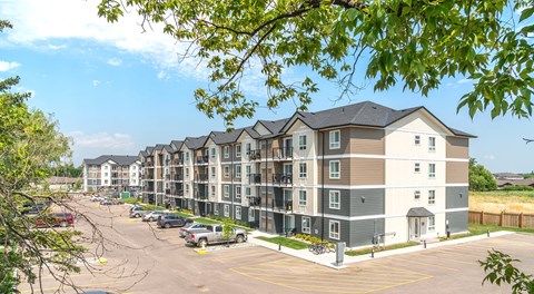A large apartment complex with a parking lot in front.