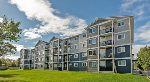 A large apartment building with a small green space in front.