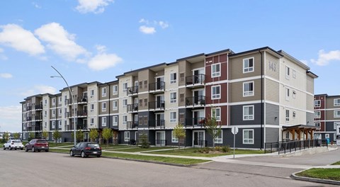 A large apartment building with street parking in front.