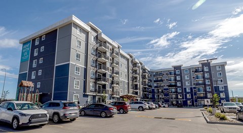 A large apartment complex with parking in front.