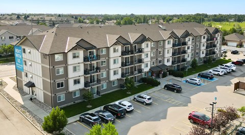 A large apartment complex with a parking lot in front.