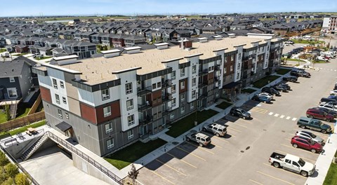 A large apartment complex with a parking lot in front.
