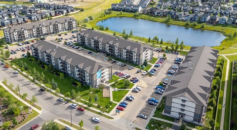 A large apartment complex with a parking lot between buildings and street parking out front