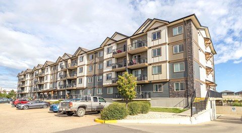 A large apartment building with a parking lot in front.