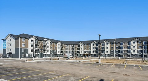 A large apartment complex with a parking lot in front.