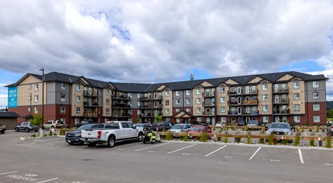 A large apartment building with lots of parking in front