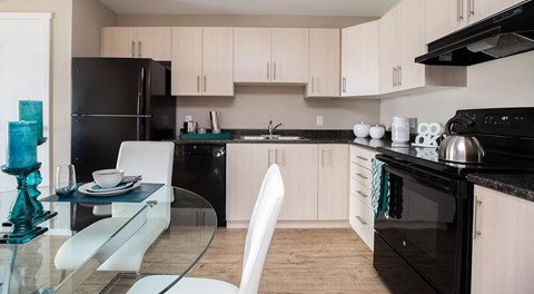 A modern kitchen with black appliances and white cabinets.