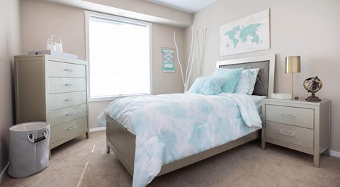 a bedroom with dresser, night stands and large window with natural light