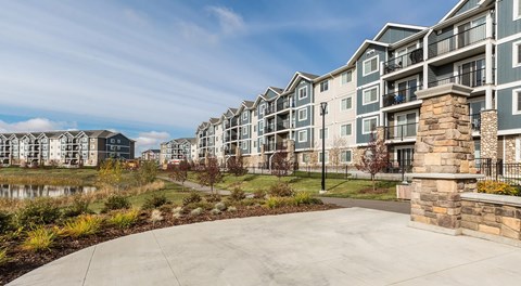 A row of modern apartment buildings with a paved walkway in front.