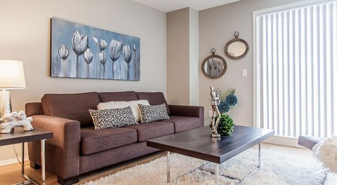 A living room with couch, end table and coffee table with large glass sliding door