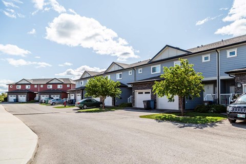 A row of houses with cars parked in front.