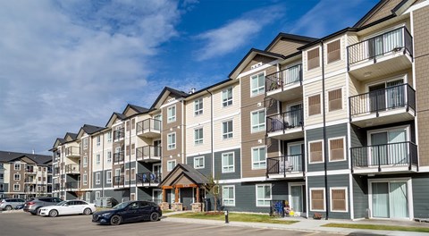 A row of modern apartment buildings with cars parked in front.