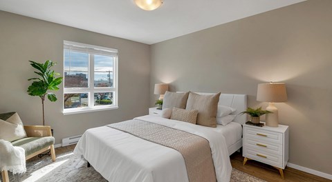 A bedroom with a large bed, a nightstand, and a chair.